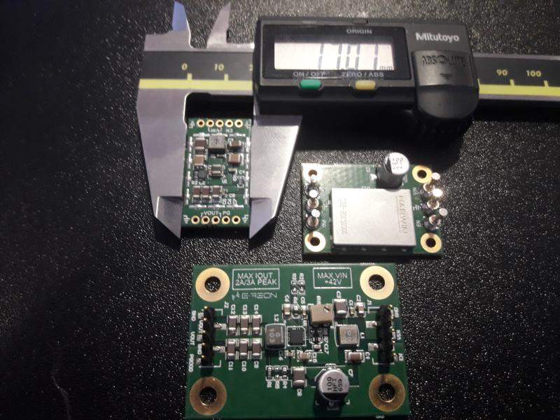 Three compact E-REON low-noise power supply modules beside a digital caliper